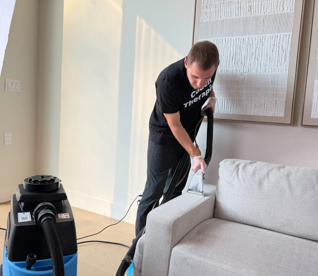Technician performing deep couch cleaning to remove stains and dirt from upholstery