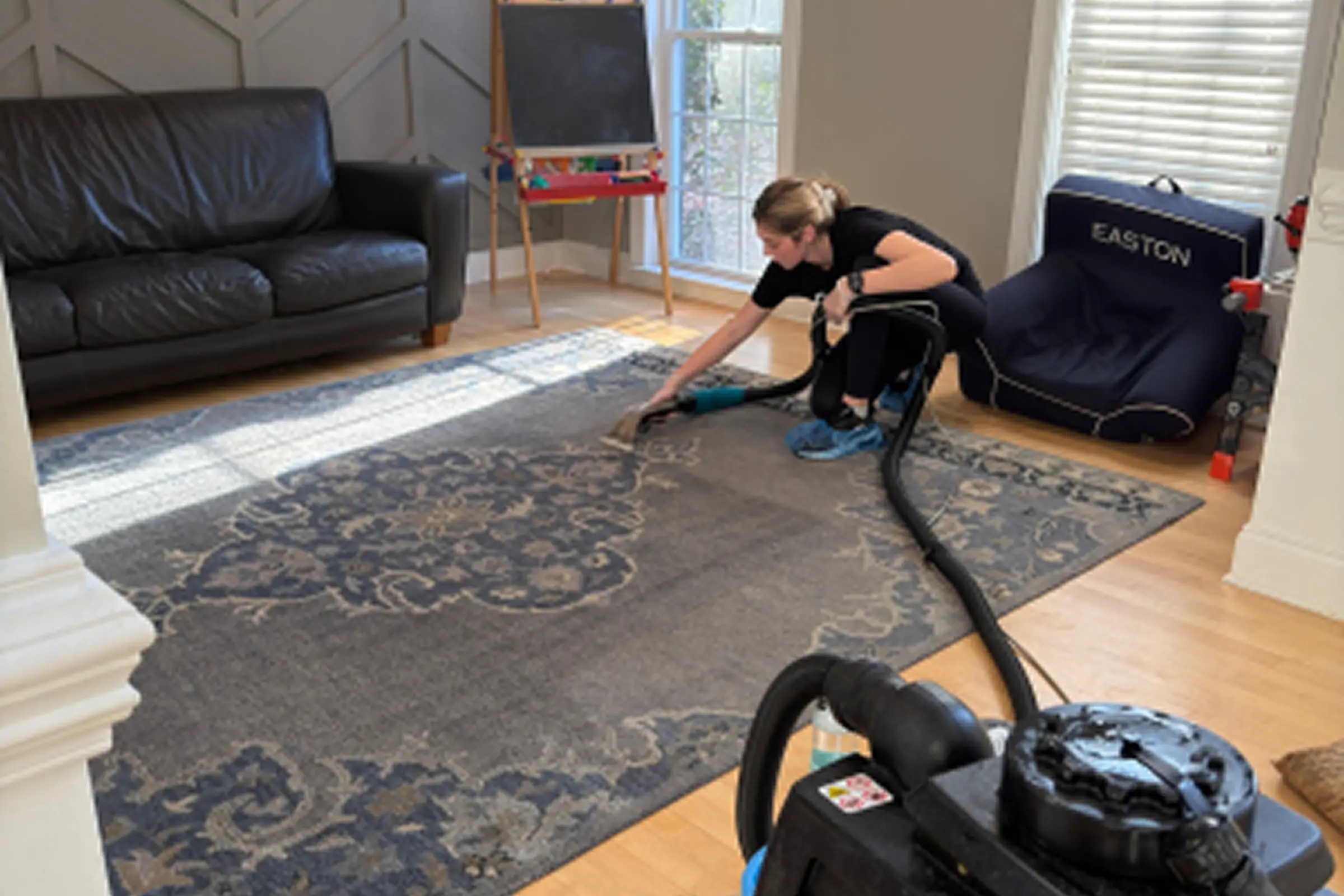 Technician performing professional area rug cleaning service in a Charlotte, NC home using steam extraction equipment