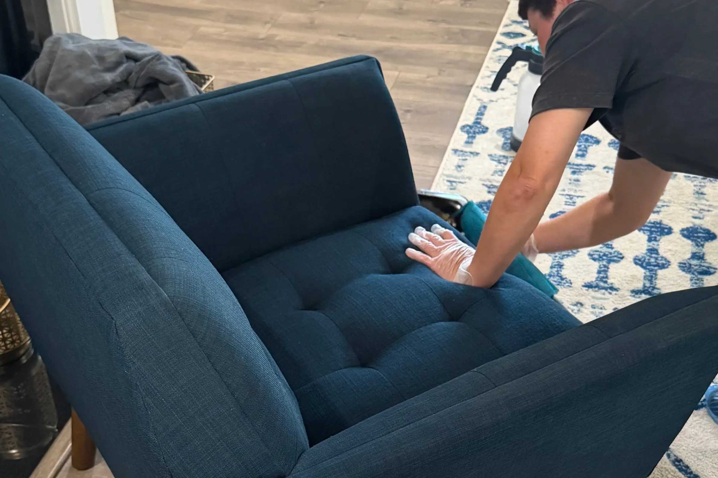 Charlotte Steamers technician in gloves performing professional upholstery cleaning on a tufted navy blue couch in Charlotte, NC