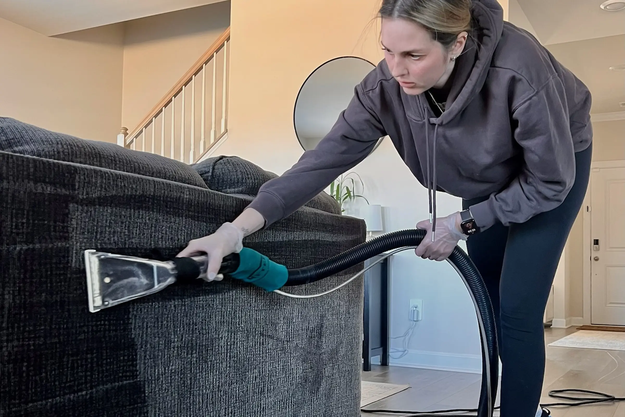 Texas Steamers technician using professional upholstery cleaning equipment on a dark gray fabric sofa during couch cleaning service in Dallas, TX