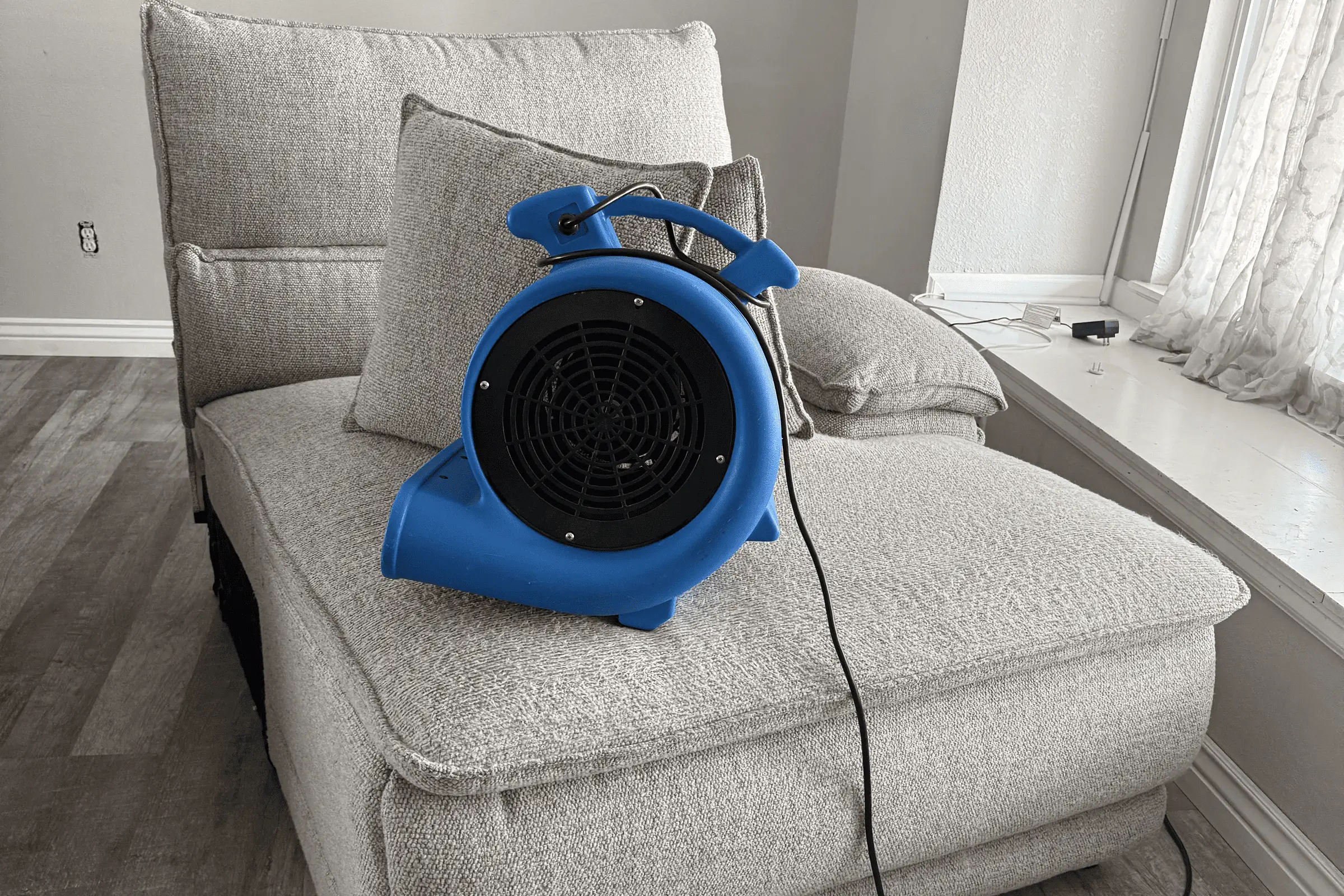 Industrial air mover placed on a gray sofa during professional upholstery cleaning service in Charlotte, NC