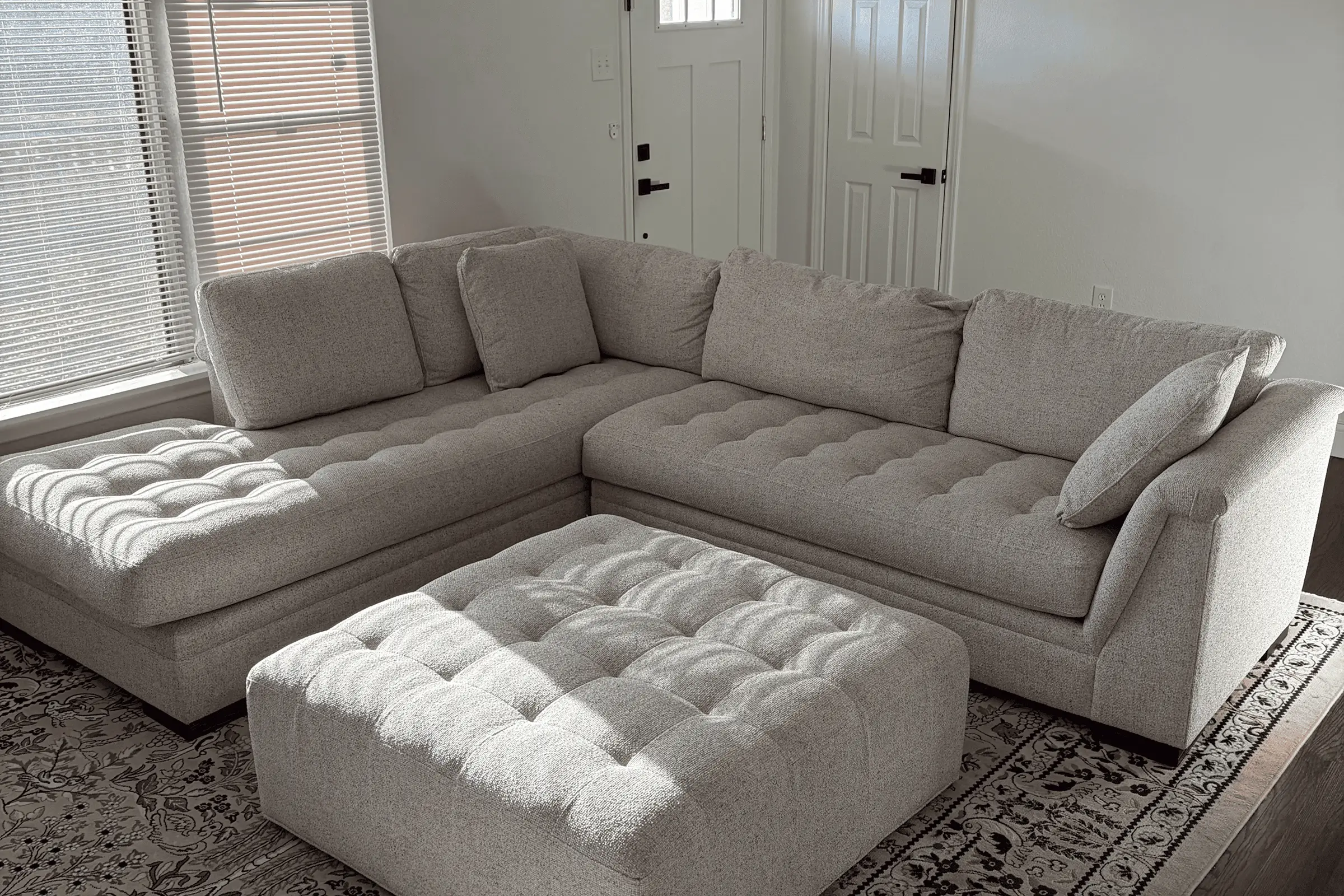 Tufted light gray sectional sofa with matching ottoman before professional upholstery cleaning services in Dallas, TX