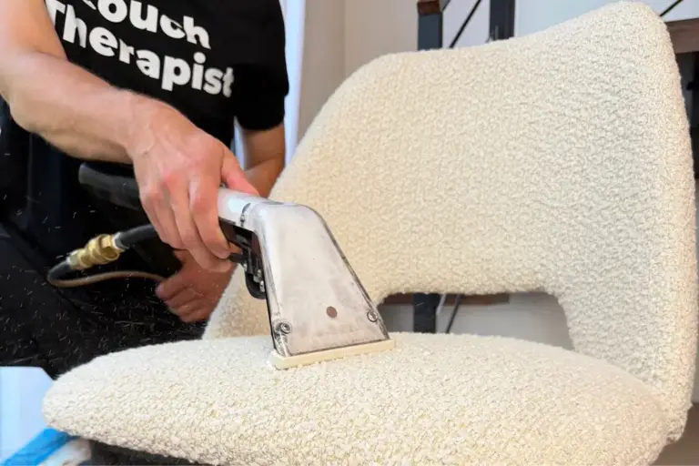 Close-up of chair upholstery cleaning on a cream bouclé fabric chair with a hot water extraction tool